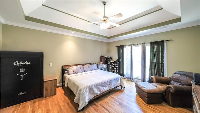 bedroom featuring crown molding, a raised ceiling, a ceiling fan, and light wood-style floors