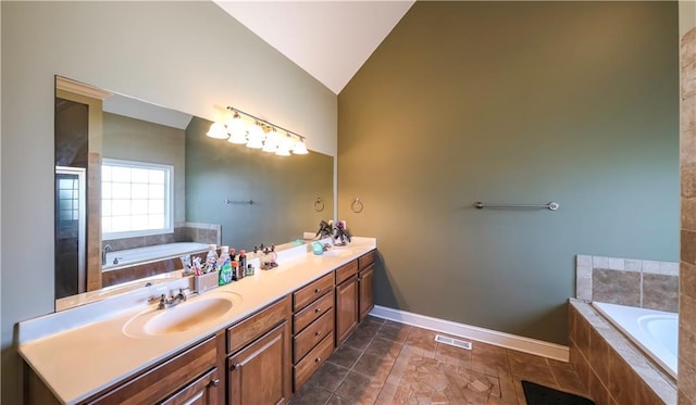 bathroom featuring a garden tub, a sink, visible vents, vaulted ceiling, and double vanity