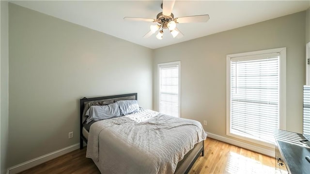 bedroom featuring ceiling fan, baseboards, and wood finished floors