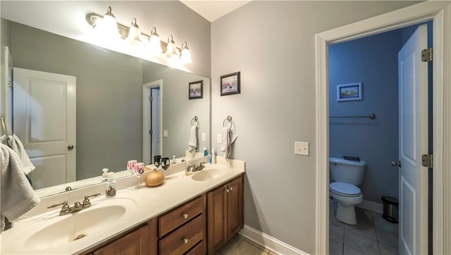 bathroom with double vanity, tile patterned flooring, a sink, and toilet