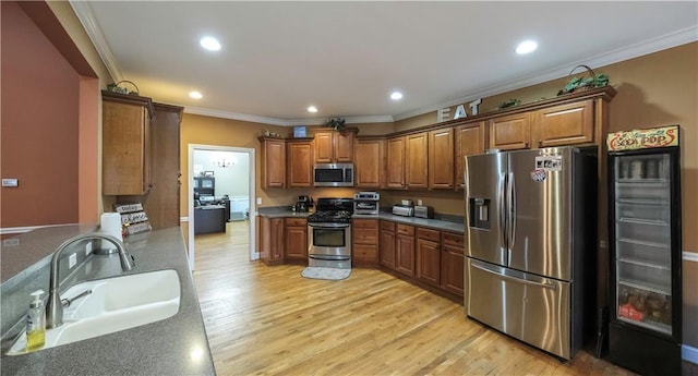 kitchen with brown cabinetry, light wood-style flooring, stainless steel appliances, and a sink