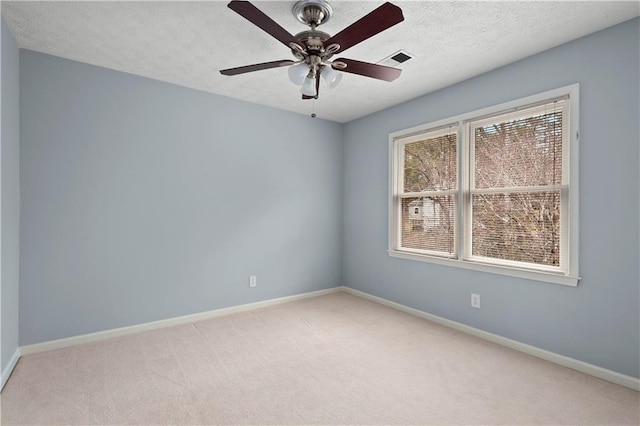 spare room with ceiling fan, light carpet, and a textured ceiling