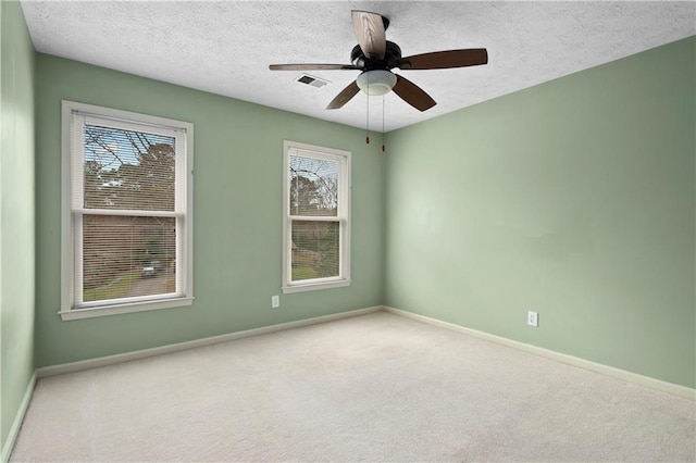 spare room with ceiling fan, light carpet, and a textured ceiling