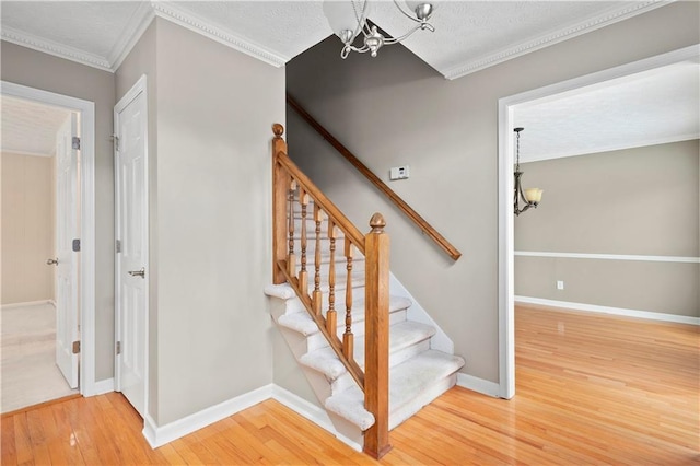 staircase featuring ornamental molding, hardwood / wood-style floors, and a chandelier