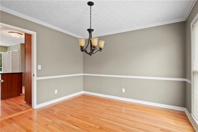 unfurnished room featuring an inviting chandelier, ornamental molding, wood-type flooring, and a textured ceiling