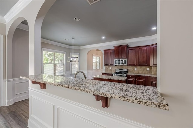 kitchen with ornamental molding, a breakfast bar area, and stainless steel appliances