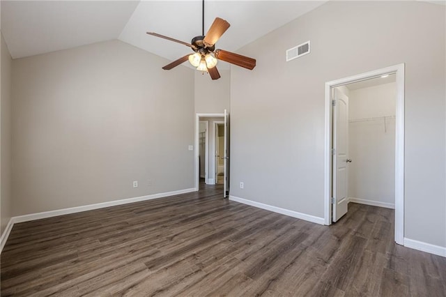 unfurnished bedroom with ceiling fan, a walk in closet, dark hardwood / wood-style flooring, and a closet