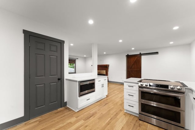kitchen with light countertops, white cabinets, stainless steel appliances, and a barn door
