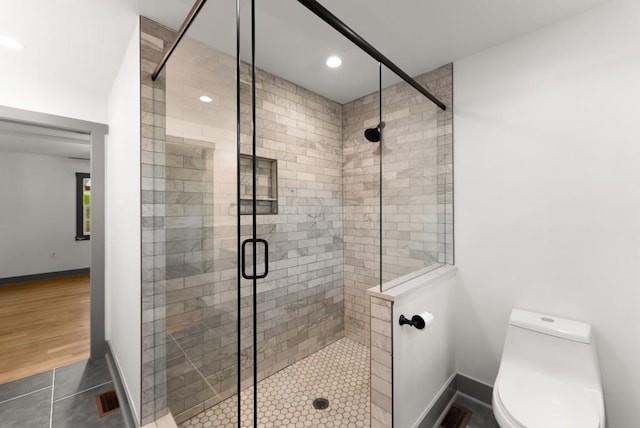 bathroom featuring baseboards, tile patterned flooring, a stall shower, and toilet