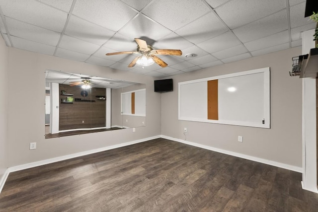 empty room featuring a ceiling fan, baseboards, a drop ceiling, and wood finished floors