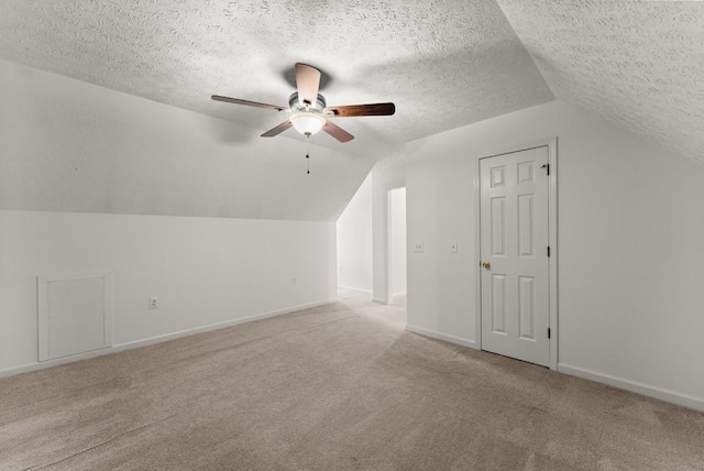 additional living space with ceiling fan, a textured ceiling, carpet floors, baseboards, and lofted ceiling