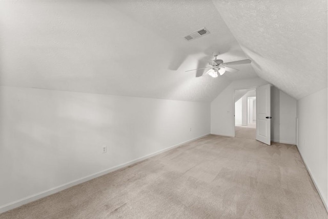 additional living space with ceiling fan, light colored carpet, visible vents, baseboards, and lofted ceiling