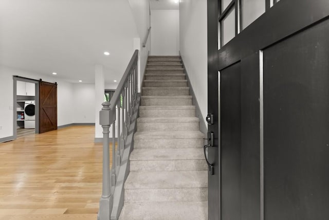 stairs featuring a barn door, recessed lighting, baseboards, washer / dryer, and wood finished floors