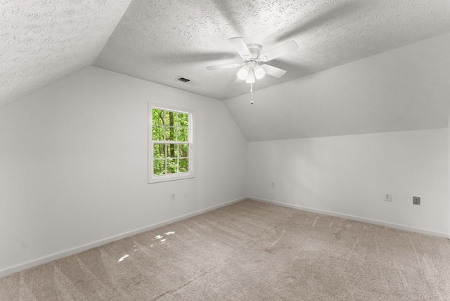 additional living space with baseboards, visible vents, light carpet, and lofted ceiling