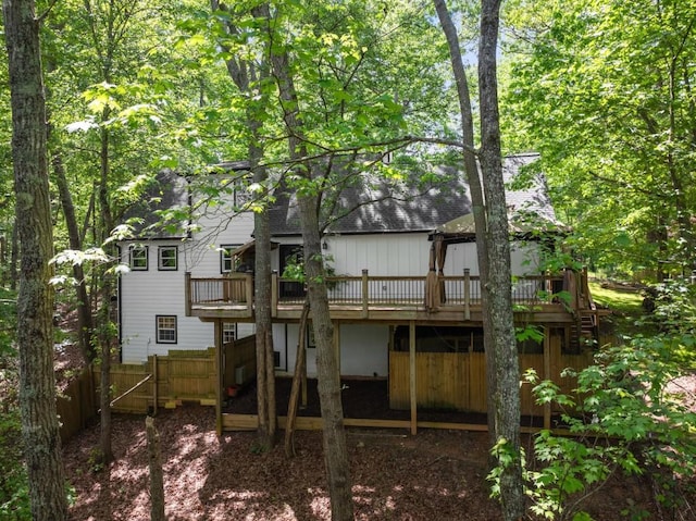 back of house with roof with shingles, a wooden deck, and fence