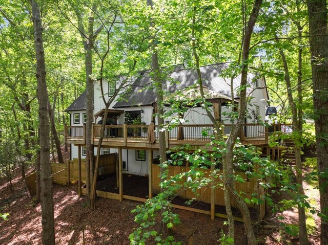 rear view of house with fence, a shingled roof, and a wooden deck