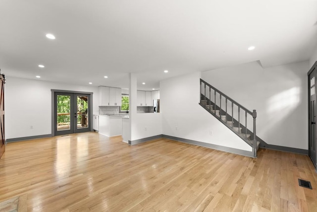 unfurnished living room with visible vents, stairs, baseboards, recessed lighting, and light wood-type flooring