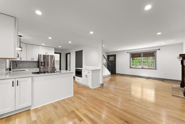 kitchen with stainless steel fridge, light countertops, a sink, and open floor plan