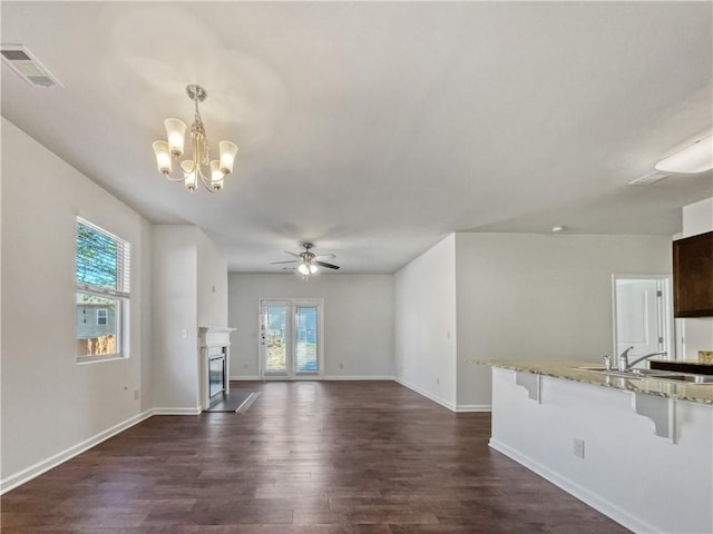 unfurnished living room featuring sink, dark hardwood / wood-style flooring, and ceiling fan with notable chandelier