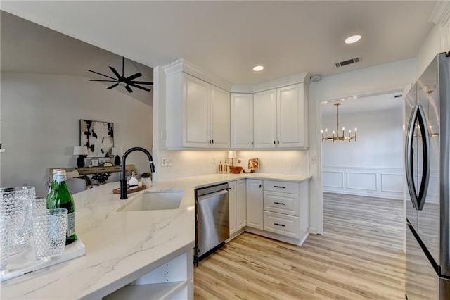 kitchen with sink, white cabinetry, hanging light fixtures, stainless steel appliances, and light stone counters