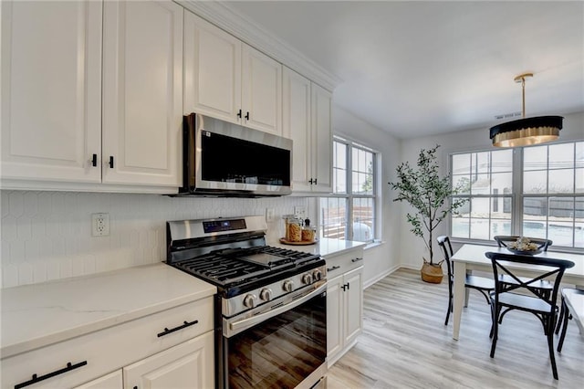 kitchen with decorative backsplash, light wood-type flooring, white cabinets, and appliances with stainless steel finishes