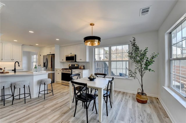 dining space featuring sink and light hardwood / wood-style flooring