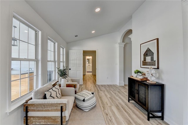 sitting room featuring ornate columns, vaulted ceiling, and light wood-type flooring