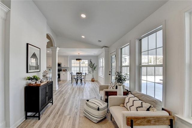 sitting room featuring lofted ceiling, light hardwood / wood-style floors, and ornate columns