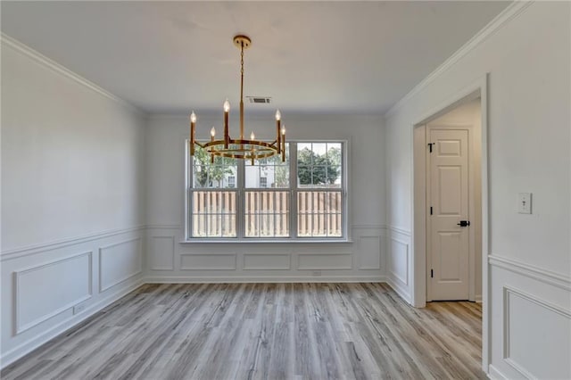 unfurnished dining area featuring ornamental molding, a chandelier, and light hardwood / wood-style flooring