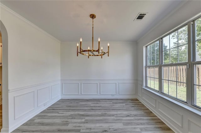 unfurnished dining area with crown molding, light hardwood / wood-style floors, and a chandelier