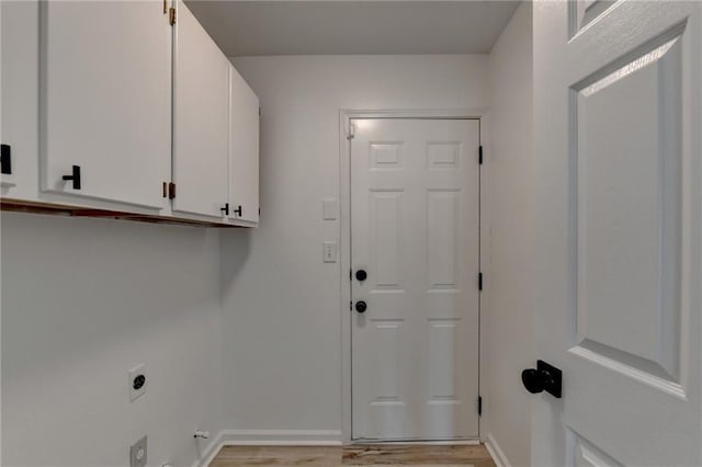 clothes washing area featuring cabinets, electric dryer hookup, and light wood-type flooring