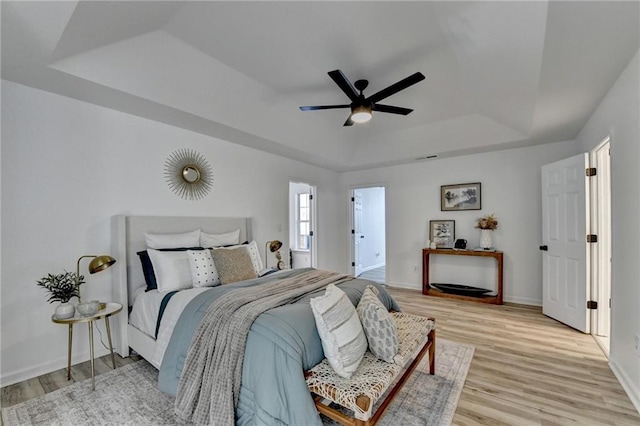 bedroom featuring a raised ceiling, ceiling fan, and light hardwood / wood-style floors