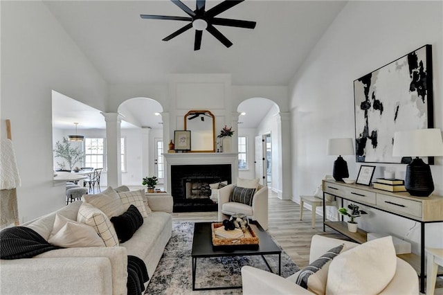 living room with decorative columns, ceiling fan, and light hardwood / wood-style floors