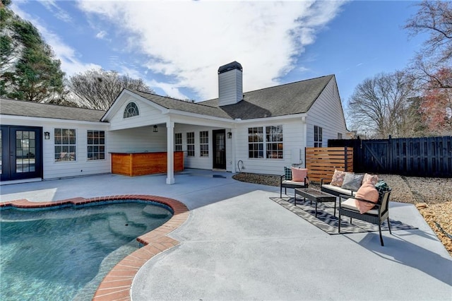 rear view of property featuring a fenced in pool, a patio, and an outdoor hangout area