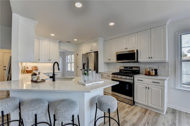 kitchen featuring white cabinetry, a breakfast bar, appliances with stainless steel finishes, and kitchen peninsula