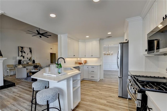 kitchen featuring a breakfast bar, sink, appliances with stainless steel finishes, kitchen peninsula, and white cabinets