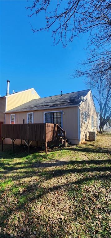 rear view of property featuring a yard and central air condition unit