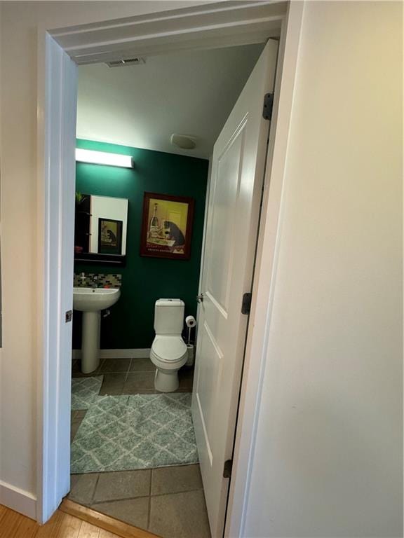 bathroom with toilet, sink, and tile patterned floors