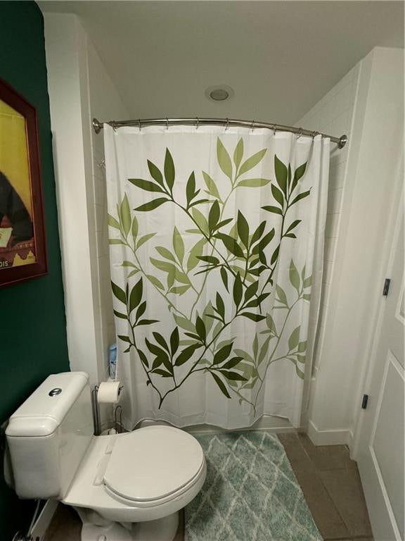 bathroom featuring a shower with shower curtain, toilet, and tile patterned floors