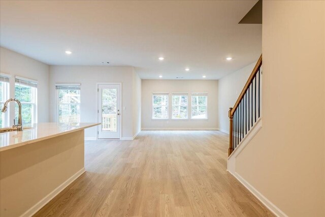 unfurnished living room featuring sink and light hardwood / wood-style floors