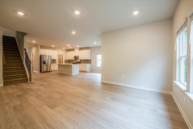 unfurnished living room with sink and light hardwood / wood-style flooring