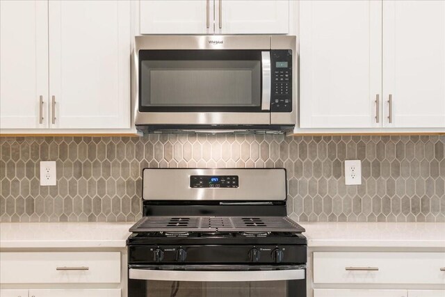 kitchen with decorative backsplash, white cabinets, and appliances with stainless steel finishes