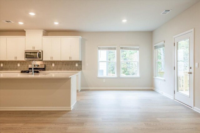 kitchen featuring white cabinetry, a healthy amount of sunlight, stainless steel appliances, and light wood-type flooring