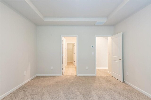 unfurnished bedroom with light colored carpet and connected bathroom