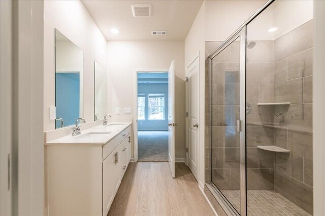 bathroom with vanity, wood-type flooring, and a shower with door