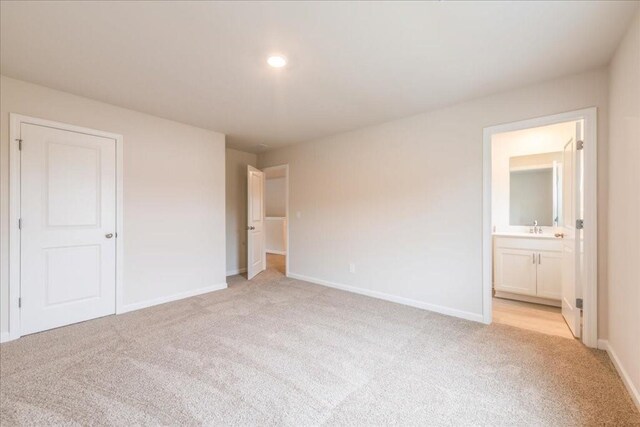 unfurnished bedroom featuring light colored carpet, sink, and connected bathroom