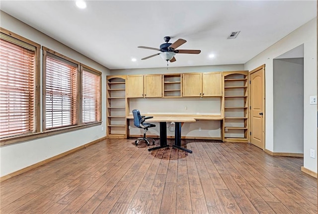 office area with built in desk, light hardwood / wood-style flooring, and ceiling fan