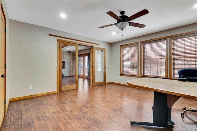 unfurnished office with ceiling fan, french doors, a healthy amount of sunlight, and wood-type flooring