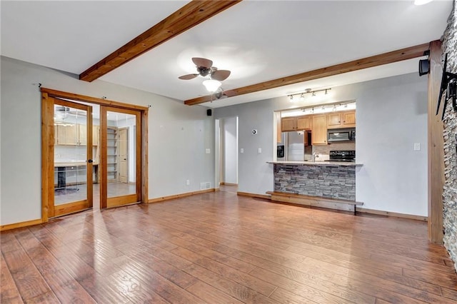 unfurnished living room with beamed ceiling, wood-type flooring, french doors, and ceiling fan