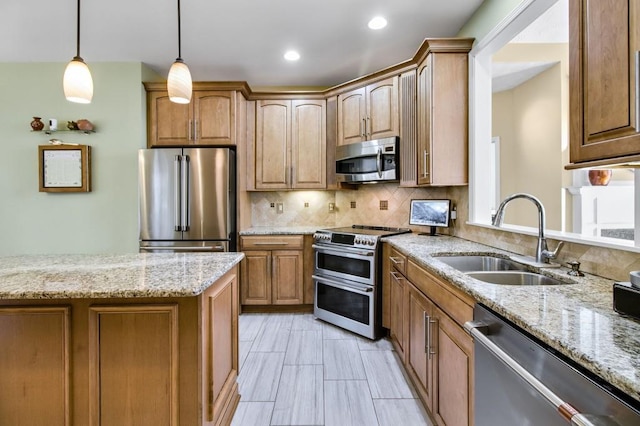 kitchen with light stone countertops, tasteful backsplash, stainless steel appliances, sink, and decorative light fixtures